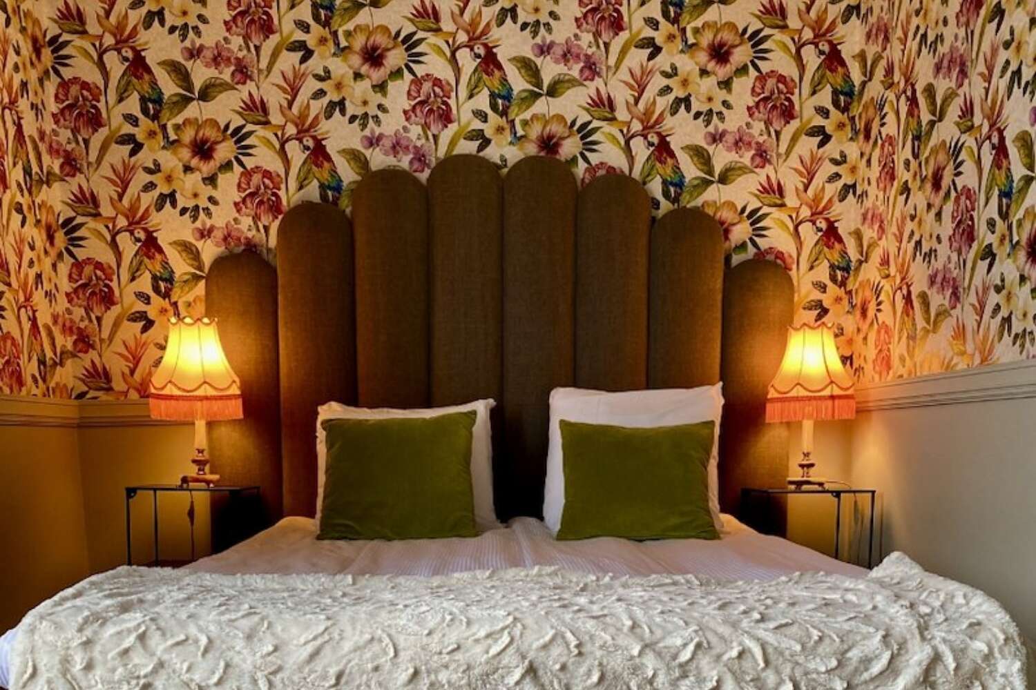 Dubbelrum med blommig tapet och gröna kuddar på Grenna Hotell