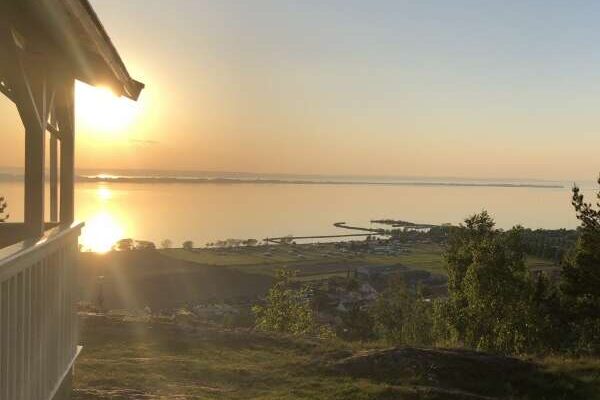 Solnedgång över Vättern sedd från höjd med byggnad i förgrunden