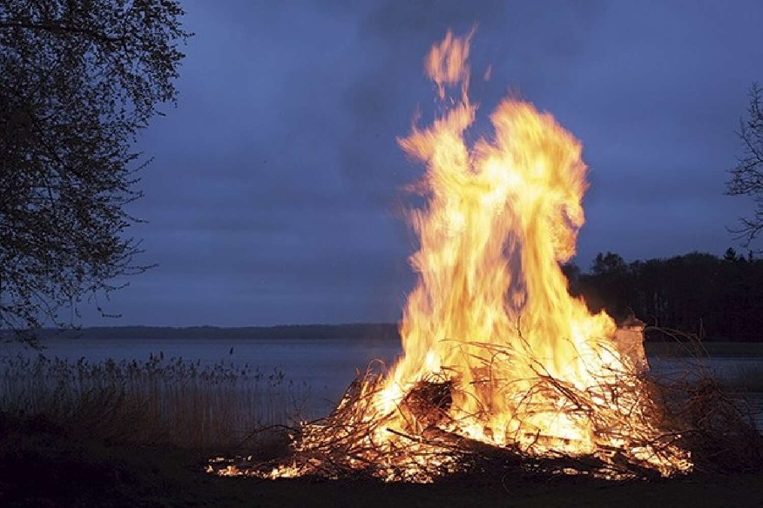 Majbrasa vid sjö i skymning