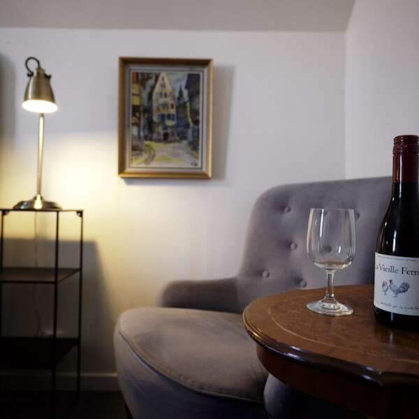 Fåtölj vid bord med vinglas och vinflaska i Dubbelrum Annex på Grenna Hotell