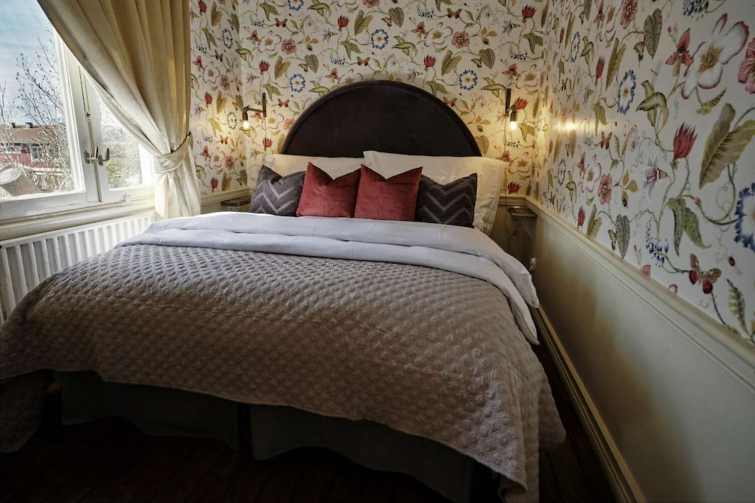 Dubbelsäng med rund sänggavel och blommig tapet