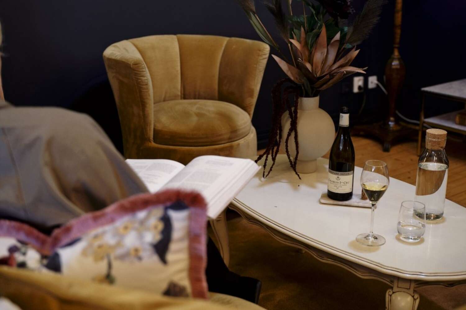 Sittgrupp med bok, vinglas och blomsterarrangemang på vitt soffbord