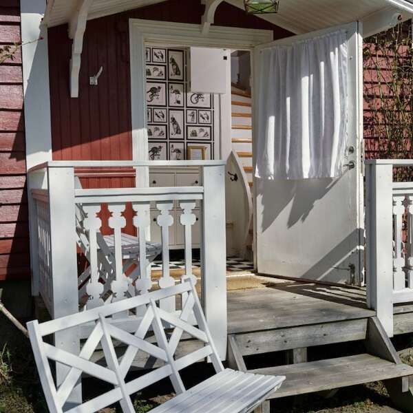 Veranda med öppen entré och vita trädetaljer vid Portvakten på Grenna Hotell